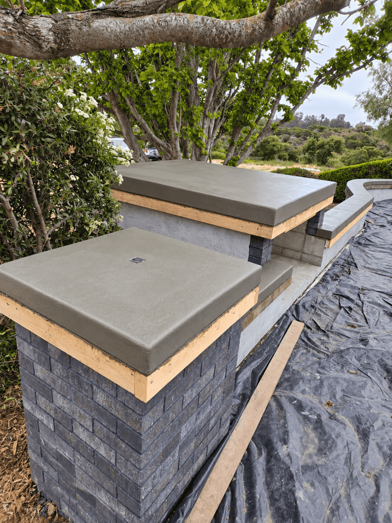Modern concrete bench and wall with brick base in outdoor setting.