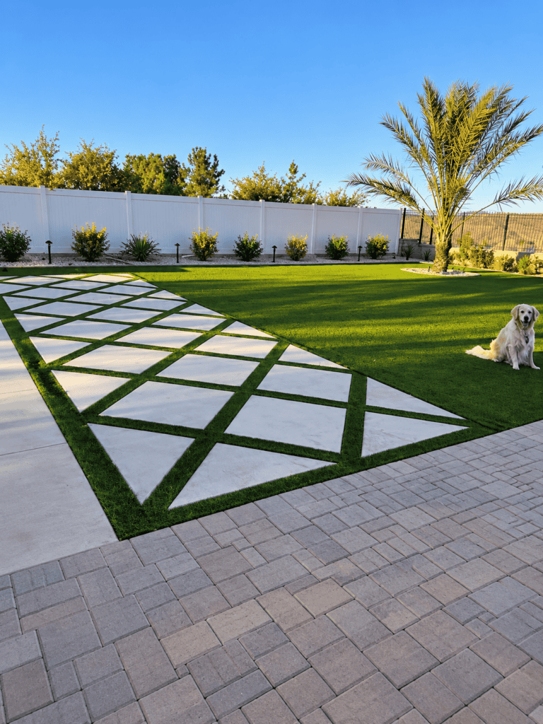 Concrete patio with geometric design, lush lawn, and palm tree in backyard.