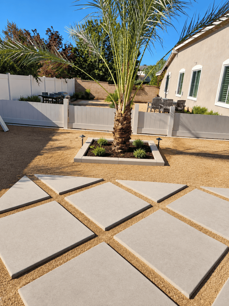 Concrete patio with large stepping stones and palm tree in backyard.