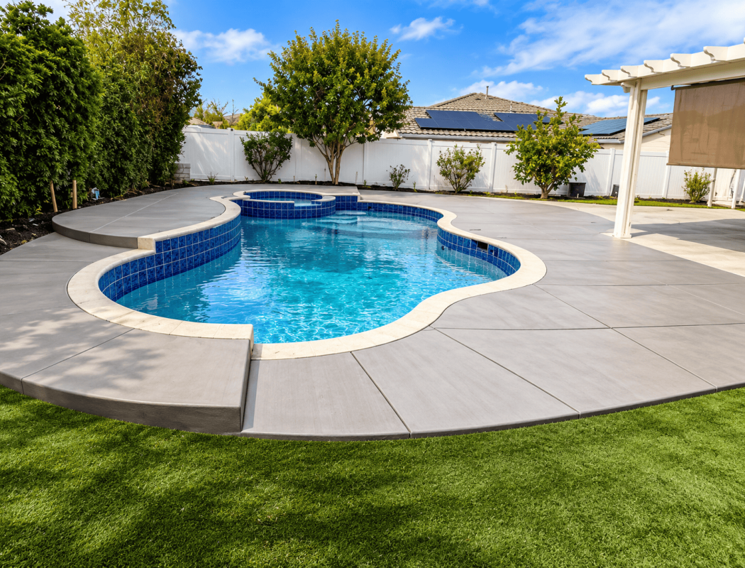 Beautiful concrete pool with blue tile interior and surrounding patio.