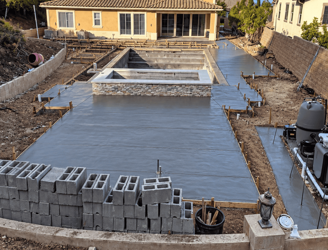 Concrete pool foundation being poured in backyard for new swimming pool.
