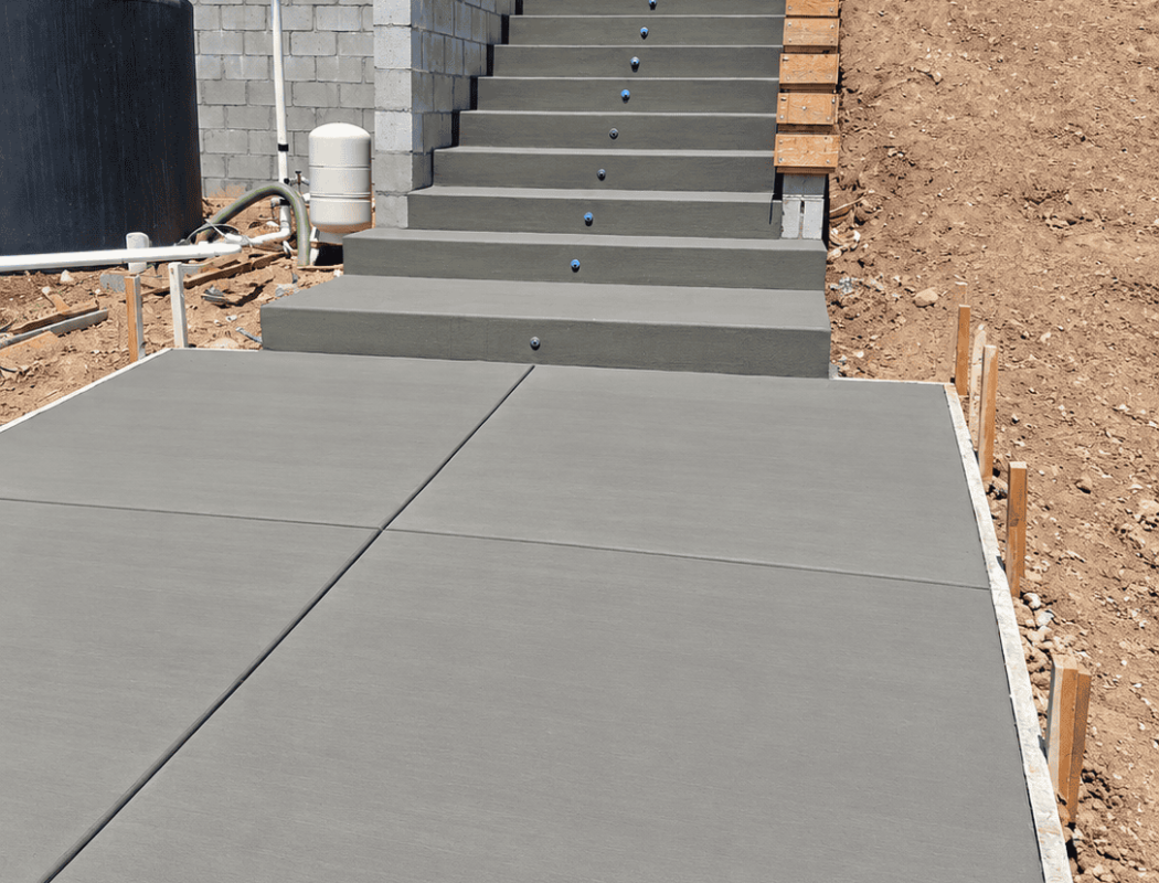 Newly poured concrete stairs and sidewalk at a construction site.