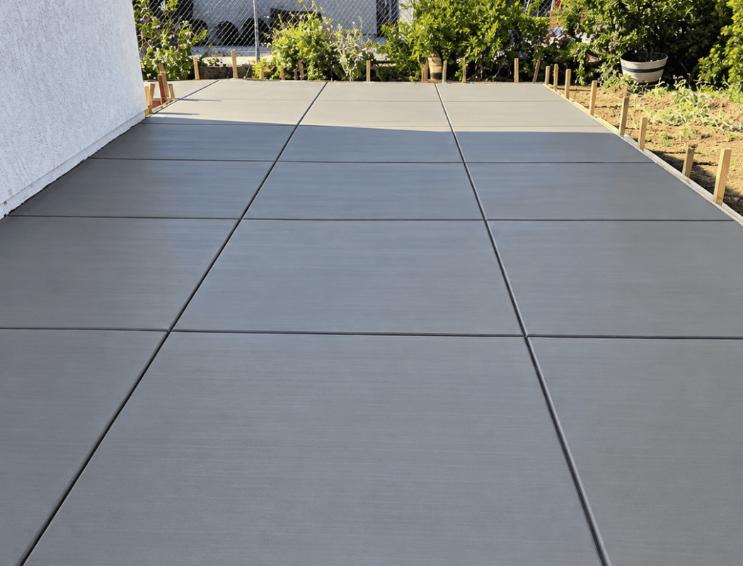 Newly poured concrete patio with clean lines and smooth finish in backyard.
